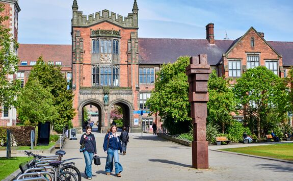 Newcastle University campus under a blue sky, featuring Gormley